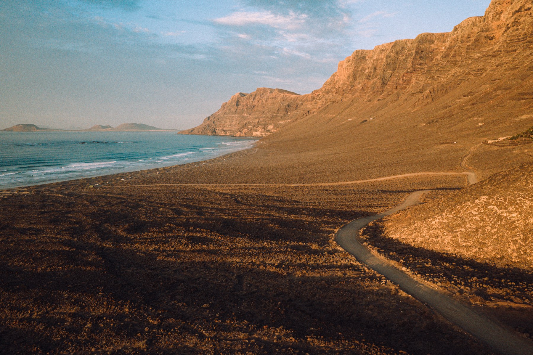 Road along the foot of high cliffs above a long beach